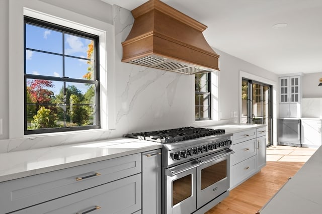 kitchen featuring custom range hood, double oven range, and a wealth of natural light