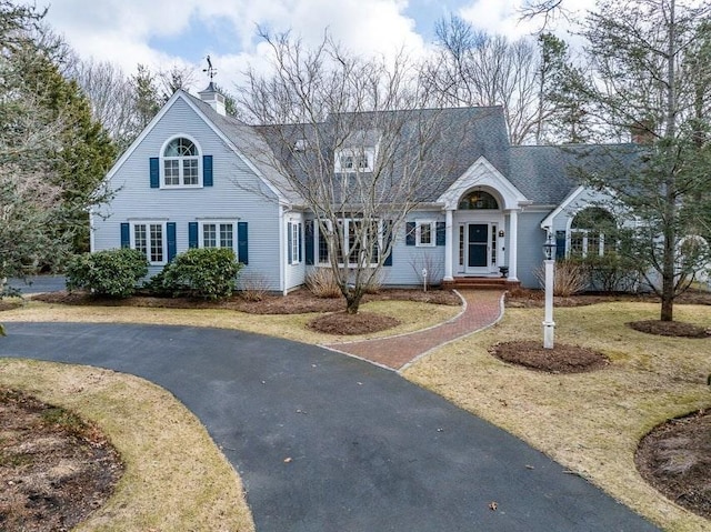 view of front of house featuring aphalt driveway, a chimney, and a shingled roof