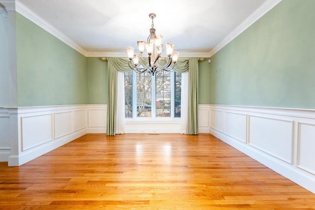 unfurnished dining area featuring light wood finished floors, a chandelier, and ornamental molding