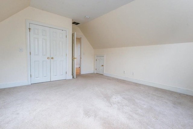 additional living space featuring visible vents, lofted ceiling, light colored carpet, and baseboards