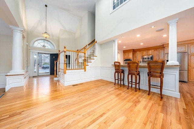 entrance foyer featuring stairway, light wood-style flooring, and ornate columns