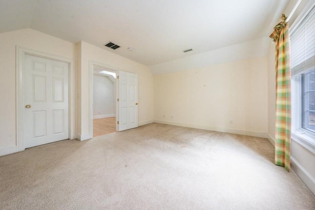 unfurnished room featuring lofted ceiling, a healthy amount of sunlight, and visible vents