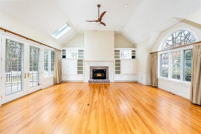 unfurnished living room featuring a wealth of natural light, a ceiling fan, wood finished floors, and a fireplace