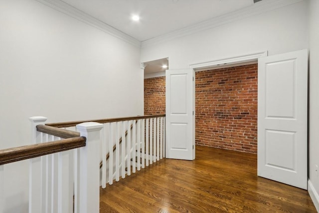 hallway with dark hardwood / wood-style flooring, ornamental molding, and brick wall