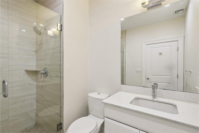 bathroom featuring a shower with door, vanity, and toilet