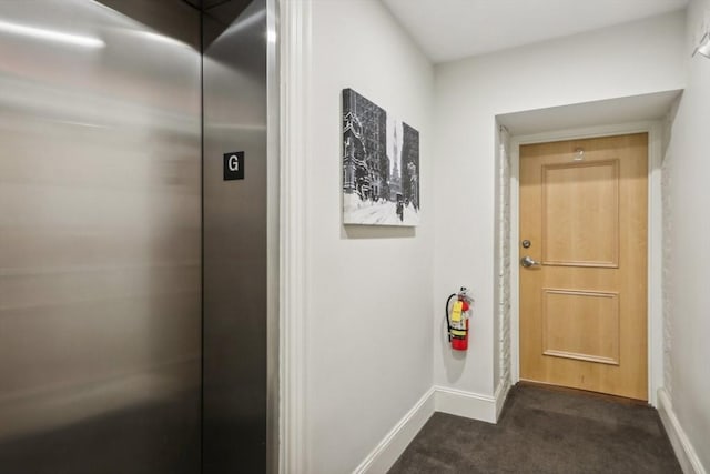 corridor featuring elevator and dark carpet