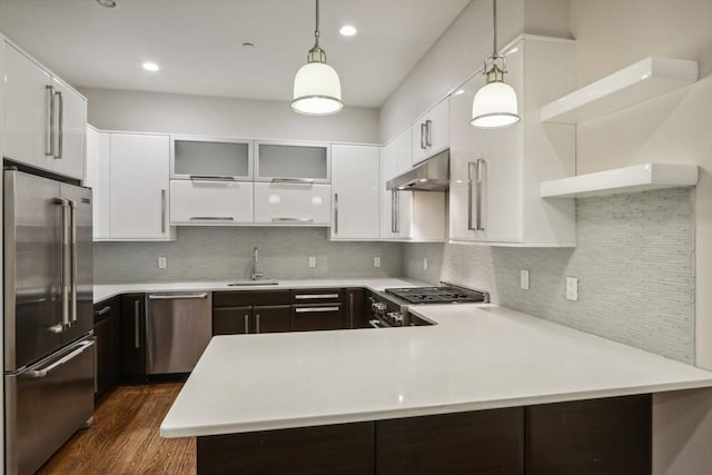 kitchen featuring kitchen peninsula, stainless steel appliances, hanging light fixtures, and sink