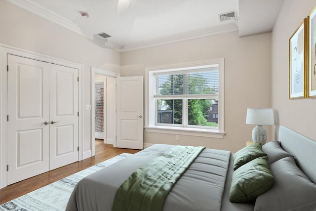 bedroom featuring ceiling fan, light hardwood / wood-style floors, crown molding, and a closet