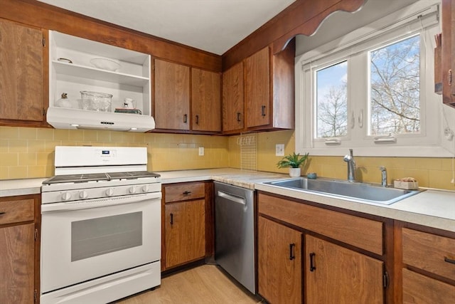 kitchen featuring ventilation hood, a sink, light countertops, white gas range oven, and stainless steel dishwasher