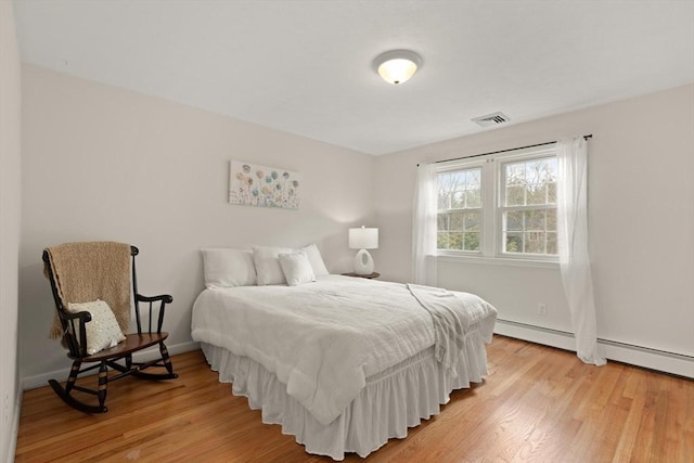 bedroom with baseboards, visible vents, light wood-type flooring, and a baseboard radiator