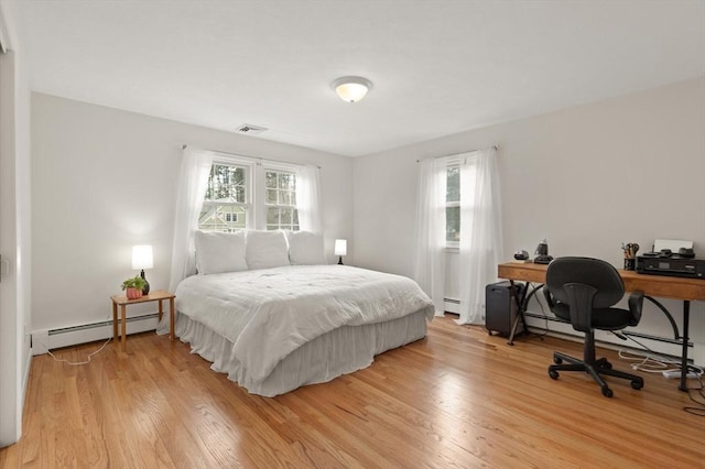 bedroom with a baseboard radiator, visible vents, and light wood finished floors