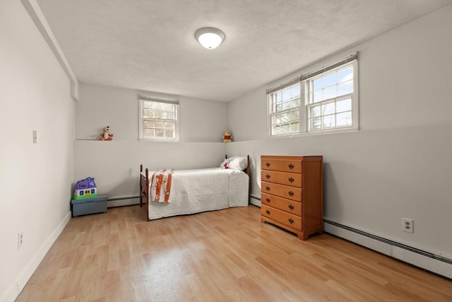 bedroom featuring a baseboard heating unit, baseboards, and wood finished floors