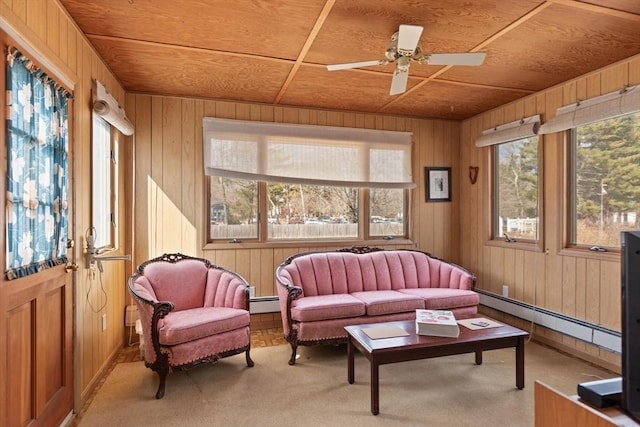 carpeted living room featuring baseboard heating, wood walls, wood ceiling, and a ceiling fan