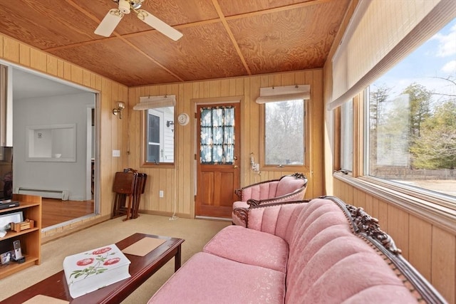 living room with a baseboard heating unit, wooden walls, carpet, wood ceiling, and ceiling fan