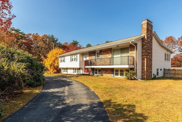 split foyer home featuring a front yard, fence, brick siding, and a chimney