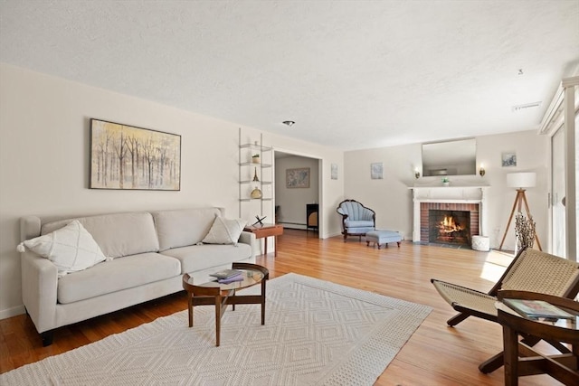 living room featuring a fireplace, light wood finished floors, and a textured ceiling