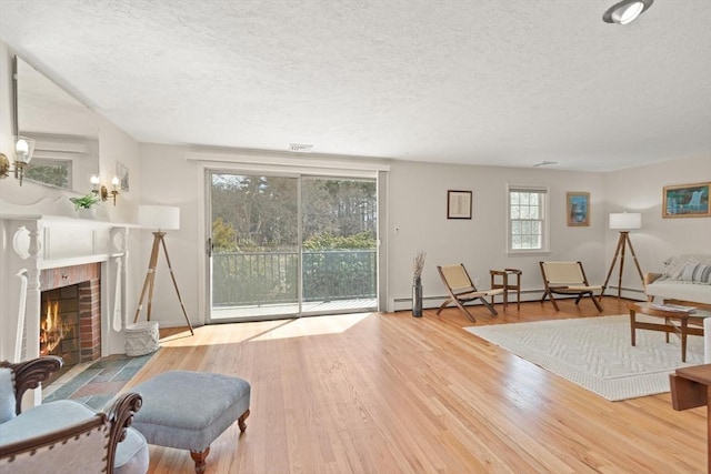 living room with a brick fireplace, a textured ceiling, and wood finished floors