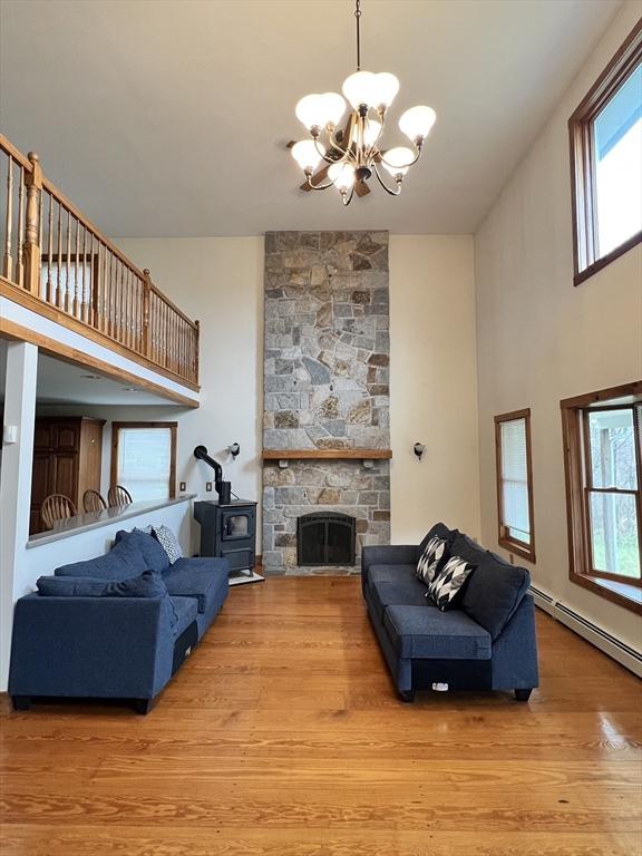 living room featuring a baseboard radiator, a wealth of natural light, wood finished floors, and a chandelier