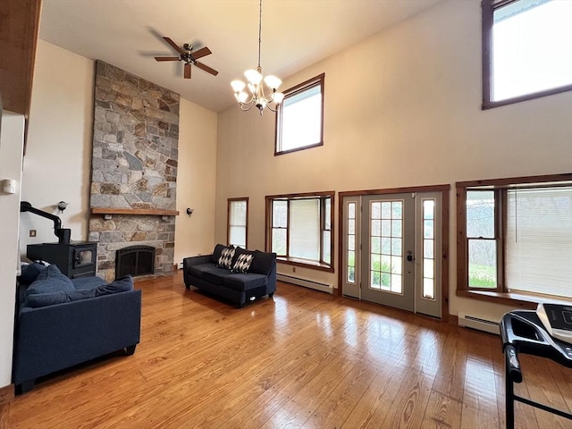living room with a high ceiling, a baseboard radiator, ceiling fan with notable chandelier, and hardwood / wood-style floors