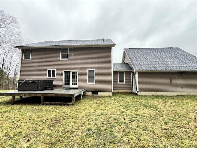 rear view of property with a shingled roof, a hot tub, and a yard