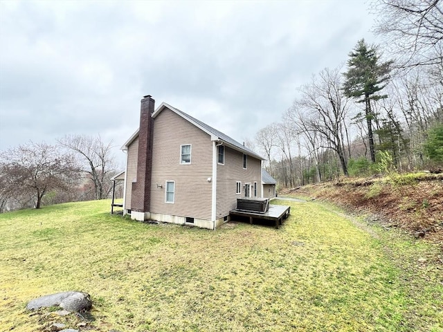 view of home's exterior with a lawn, a wooden deck, and a chimney