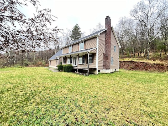 rear view of property featuring a yard, a chimney, and a porch