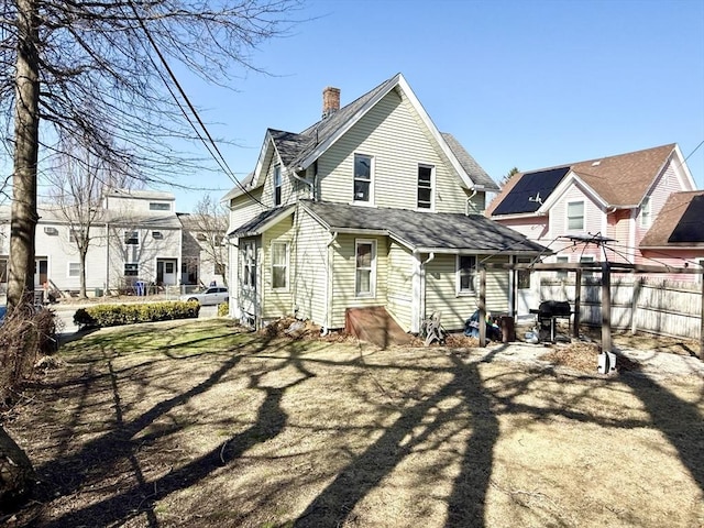 129 Eastern Ave, Springfield, MA 01109 - back of property with a chimney, a shingled roof, and fence