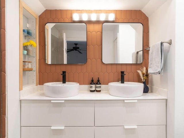 full bath featuring ceiling fan, tasteful backsplash, double vanity, and a sink