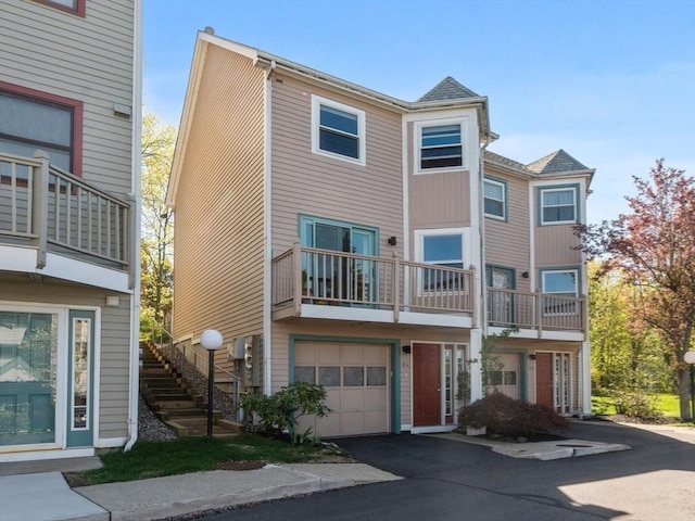 view of property featuring stairs, a garage, and driveway