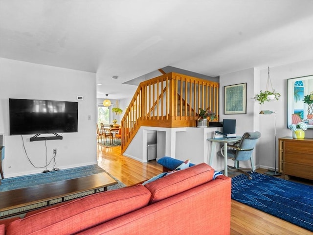 living room with stairs, baseboards, and wood finished floors