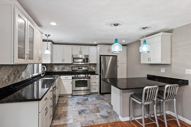 16 Deer Path Unit 1, Maynard, MA 01754 - kitchen with stainless steel appliances, a sink, a peninsula, white cabinets, and decorative backsplash