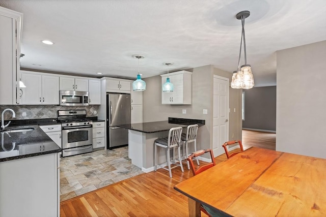 16 Deer Path Unit 1, Maynard, MA 01754 - kitchen with appliances with stainless steel finishes, a sink, a peninsula, white cabinets, and recessed lighting