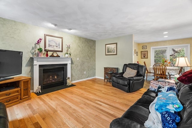 living area with a fireplace with flush hearth, baseboards, and wood finished floors