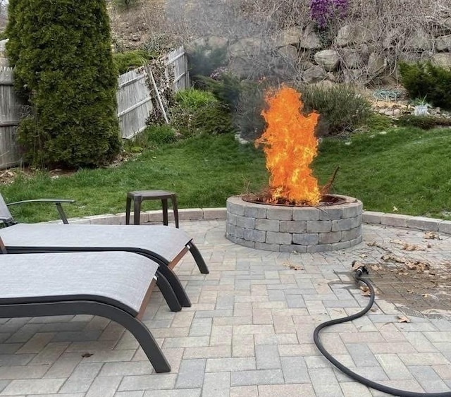 view of property's community featuring an outdoor fire pit, fence, and a patio