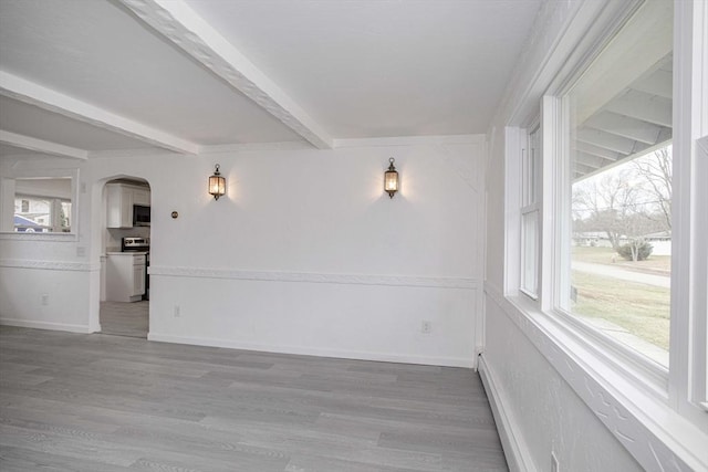 spare room with beamed ceiling, wood-type flooring, and a baseboard heating unit