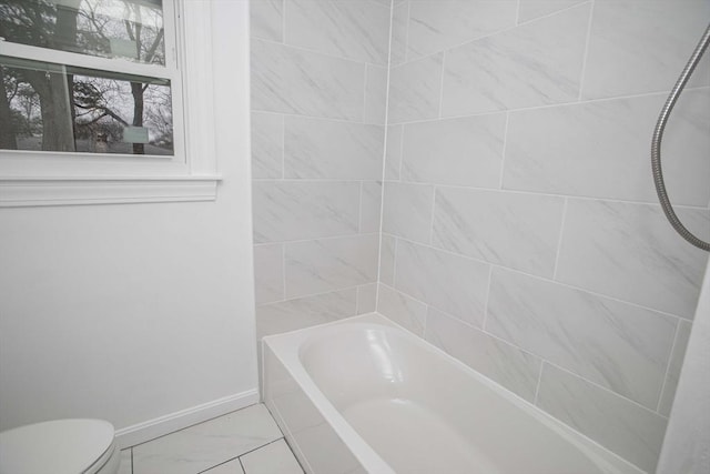 bathroom featuring tiled shower / bath combo and toilet