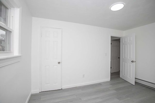 unfurnished bedroom with light wood-type flooring and a baseboard radiator