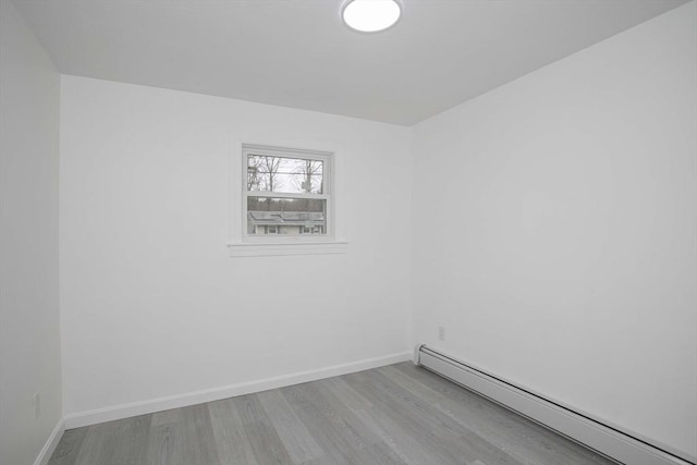 unfurnished room featuring a baseboard radiator and light hardwood / wood-style floors