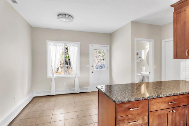 kitchen with backsplash, light tile patterned floors, and dark stone countertops