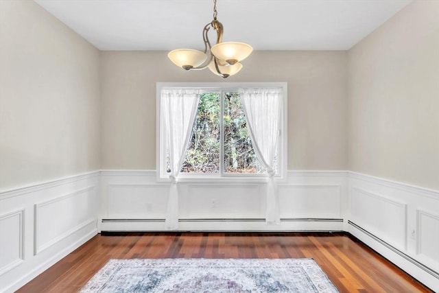 unfurnished dining area with dark wood-type flooring, a notable chandelier, and baseboard heating