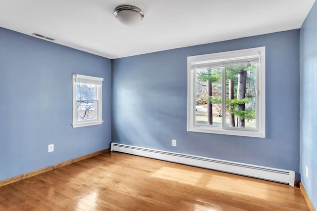 empty room featuring light hardwood / wood-style flooring, a baseboard radiator, and plenty of natural light