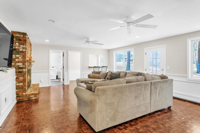 living room with ceiling fan, dark parquet flooring, washer / dryer, and a baseboard heating unit