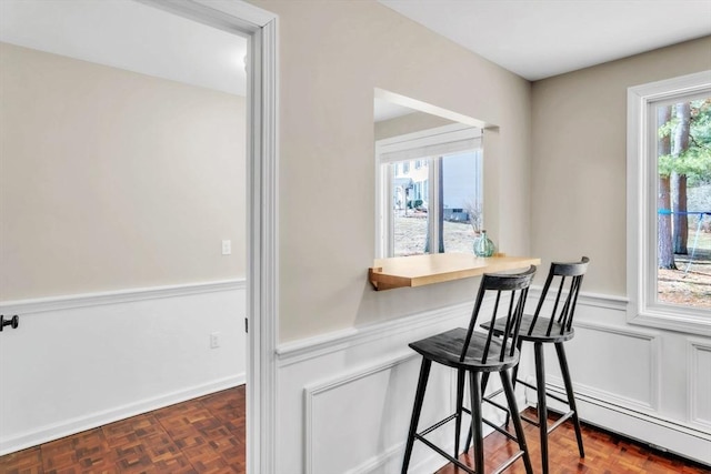 interior space featuring a baseboard heating unit, dark parquet flooring, and a kitchen bar