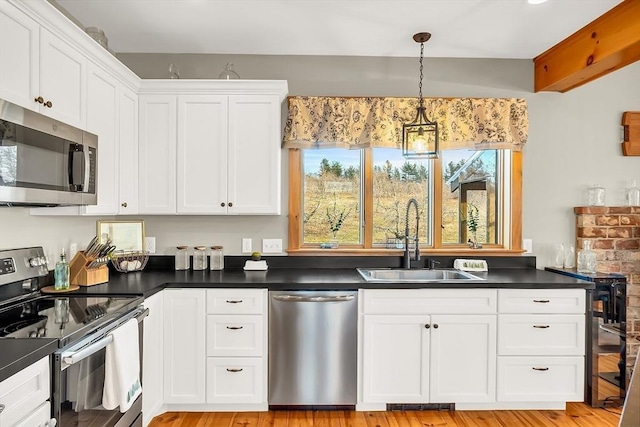 kitchen with sink, hanging light fixtures, stainless steel appliances, light hardwood / wood-style floors, and white cabinets