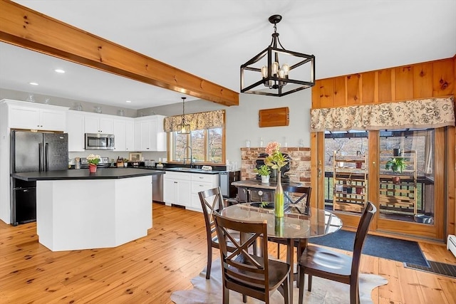 interior space with white cabinets, decorative light fixtures, beamed ceiling, and sink