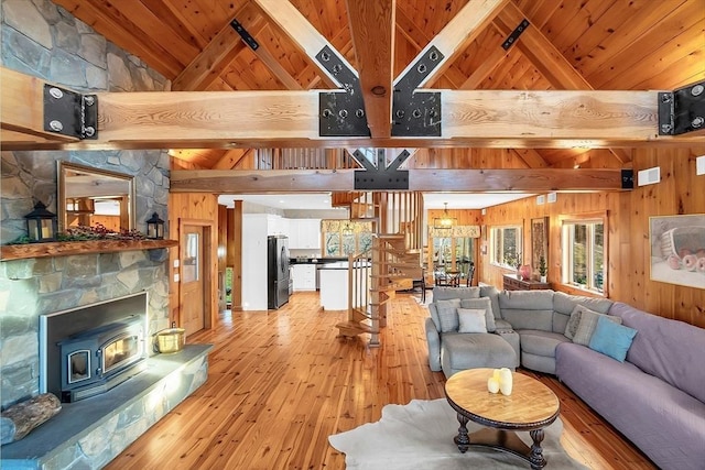 living room featuring light wood-type flooring, wooden ceiling, a wood stove, and wooden walls