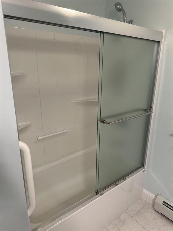 bathroom featuring a baseboard heating unit and bath / shower combo with glass door