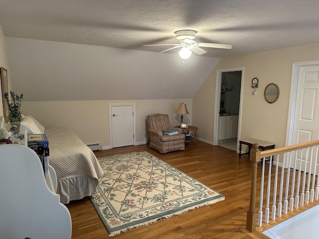 bedroom featuring lofted ceiling, a baseboard heating unit, hardwood / wood-style flooring, and ceiling fan