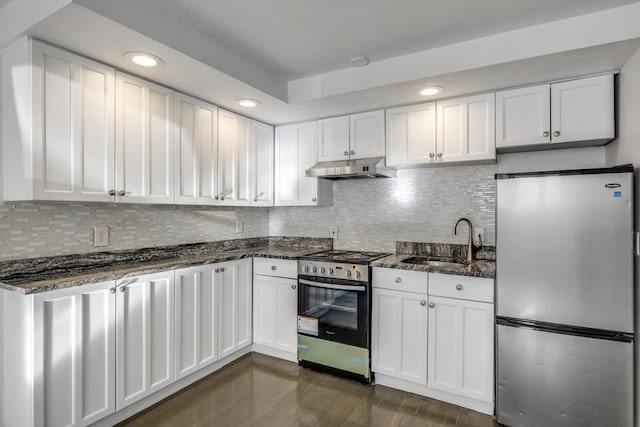 kitchen featuring dark hardwood / wood-style flooring, stainless steel appliances, sink, dark stone countertops, and white cabinetry