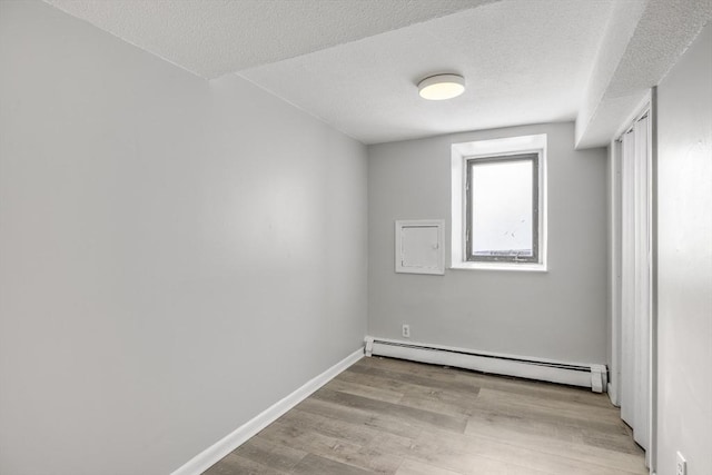 unfurnished room with a textured ceiling, a baseboard radiator, and light hardwood / wood-style flooring